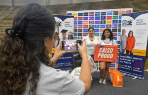 A parent and college-bound student taking a photo in front of the SAISD Foundation backdrop.