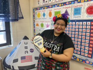 Ms. Gonzalez in her classroom with her grant winner sign.