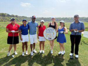 Student golfers with players at annual tournament.